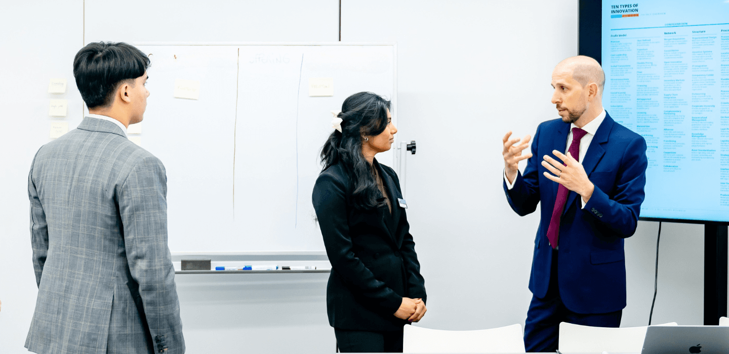 HIM Business School lecturer and students looking at data and discussing